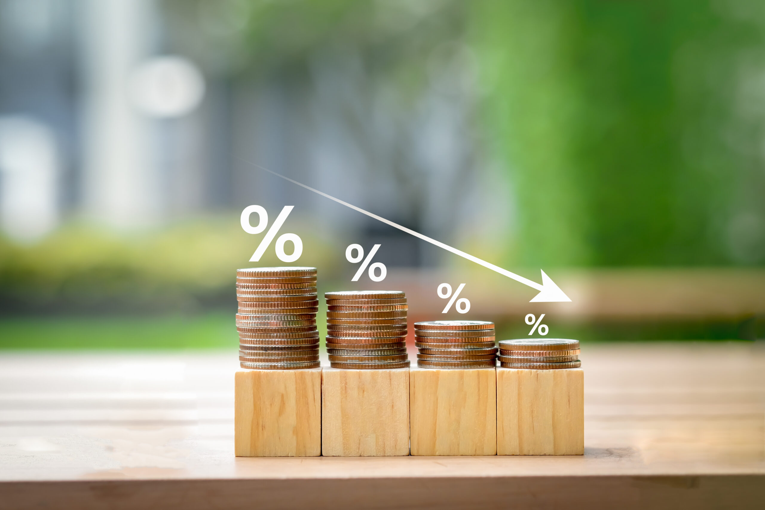 Stacks of coins decreasing in height with percentage symbols, representing cost reduction and financial efficiency strategies
