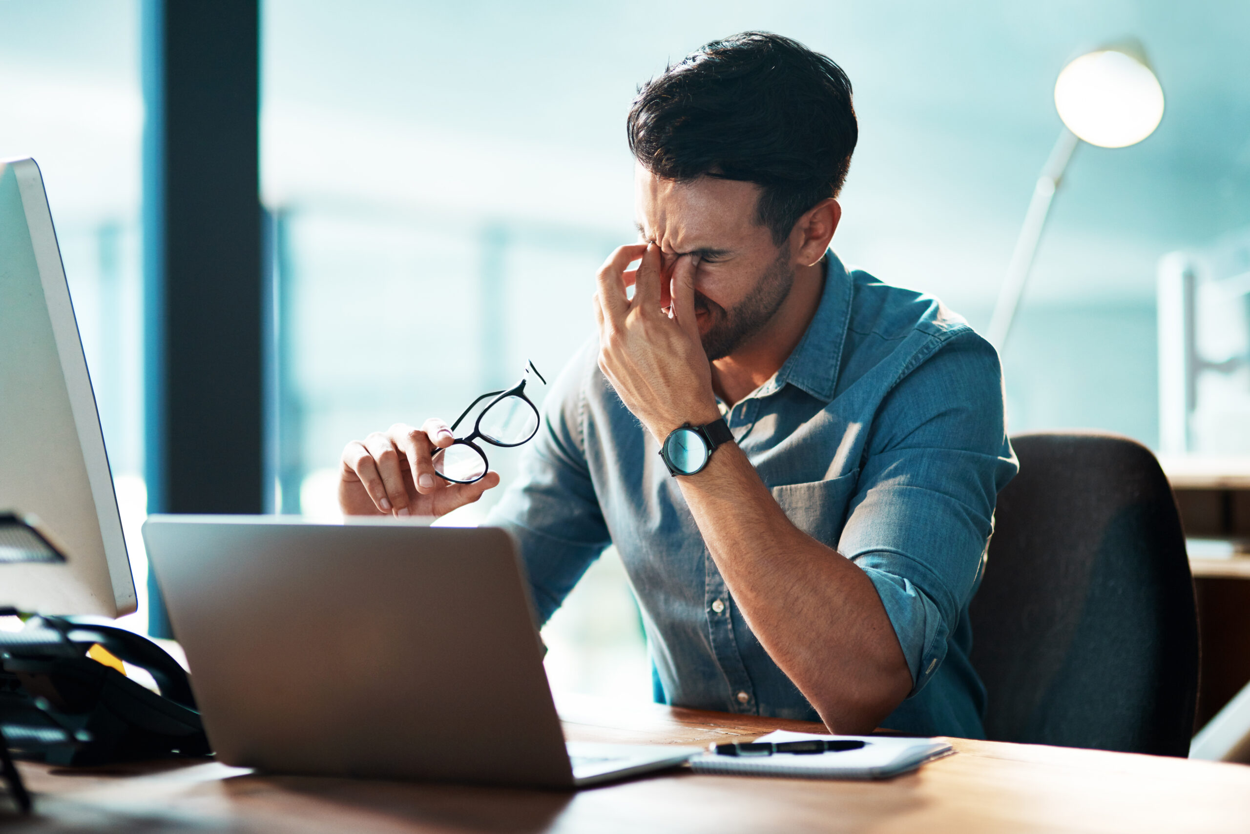 Frustrated man at desk, struggling with disconnected tools and overwhelming workload.